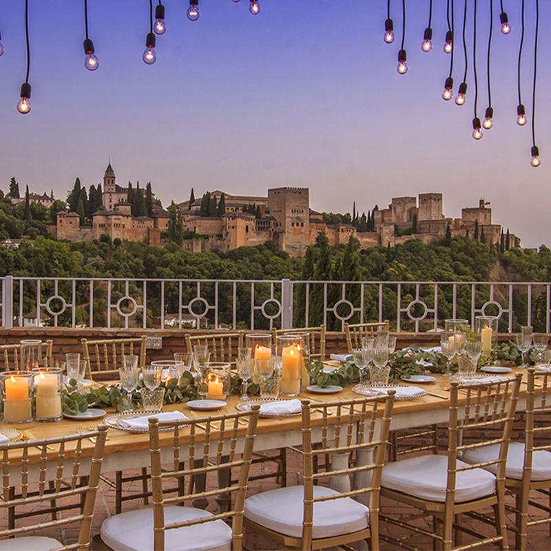 bodas-elcamborio-granada-galeria-21 Montaje de mesa de boda en terraza de El Camborio al anochecer con vistas a la Alhambra de Granada