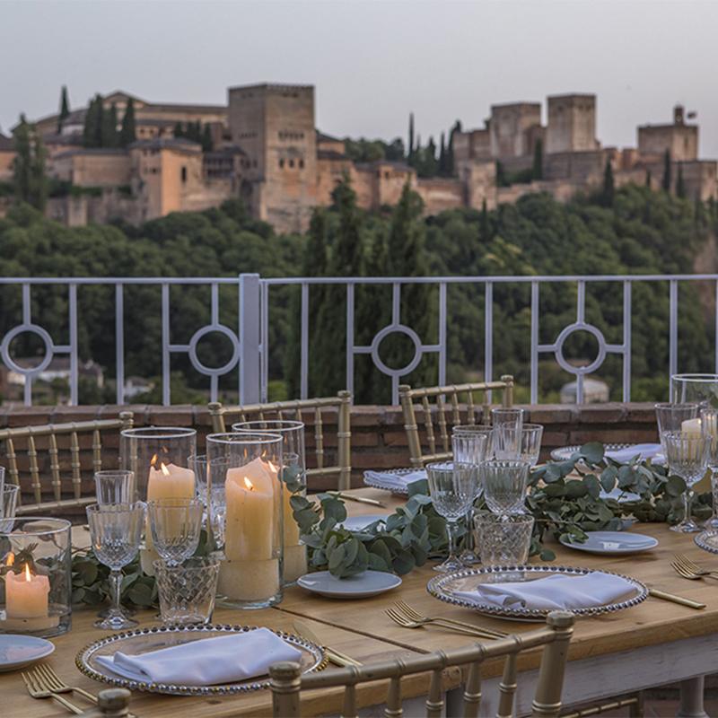 elcamborio-eventos-sociales-granada-10 Mesa al aire libre preparada para una boda en El Camborio, con elegantes detalles y vistas panorámicas de la Alhambra de Granada