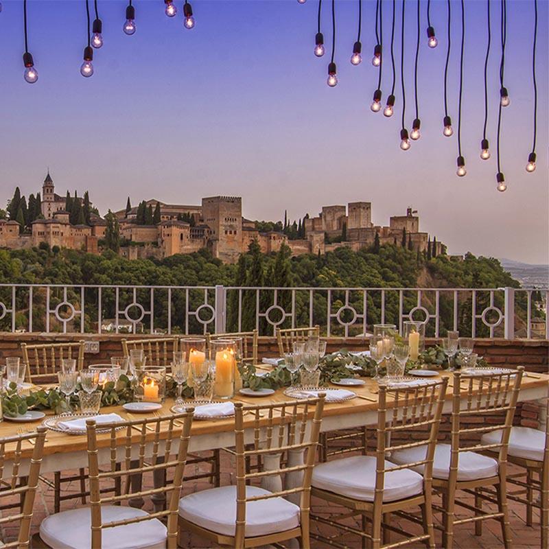 elcamborio-eventos-sociales-granada-13 Mesa al aire libre preparada para una boda en El Camborio, con elegantes detalles y vistas panorámicas de la Alhambra de Granada