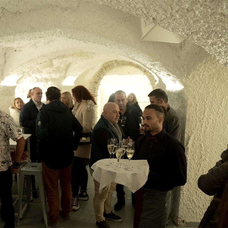 Evento social en la zona de la cueva de El Camborio, con un camarero sirviendo copas de cava en un espacio típico del Sacromonte