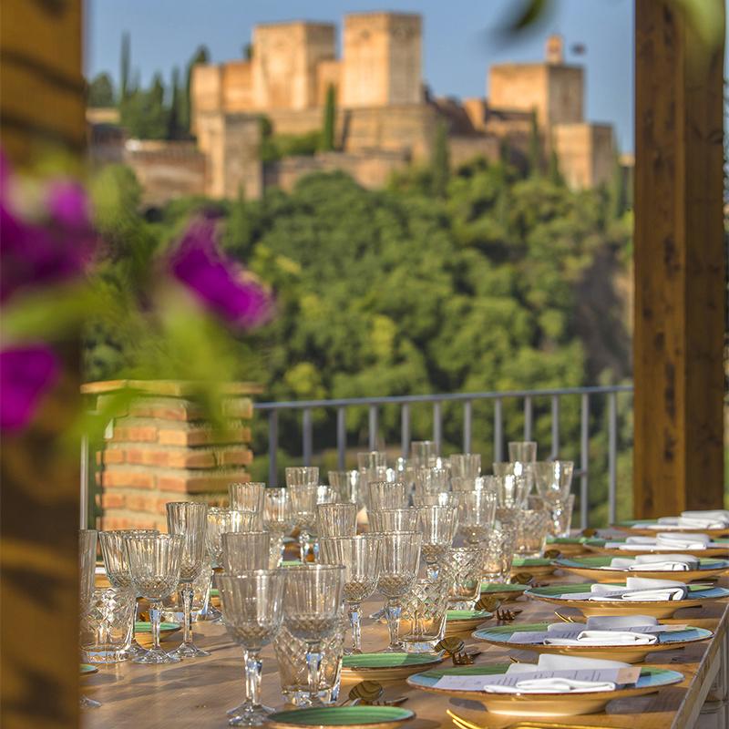 elcamborio-eventos-sociales-granada-2 Mesa decorada para una boda en El Camborio, al aire libre, con vistas a la Alhambra de Granada al fondo