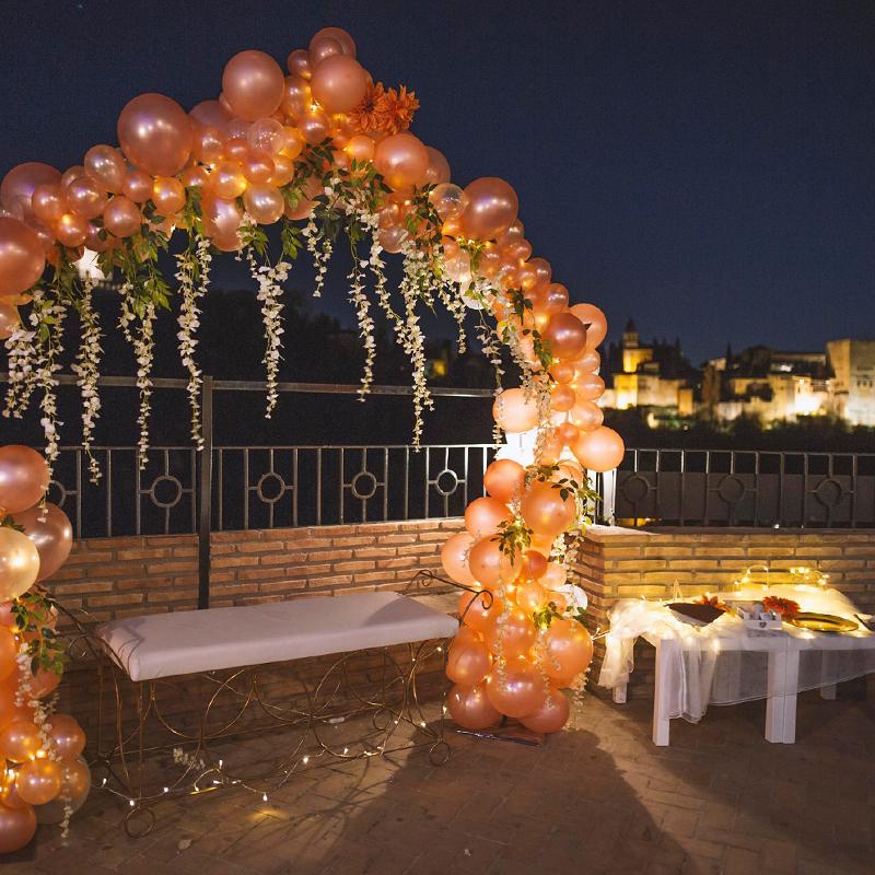 elcamborio-eventos-sociales-granada-20 Arco de globos decorativo para fotos en El Camborio, con la Alhambra de Granada visible al fondo.
