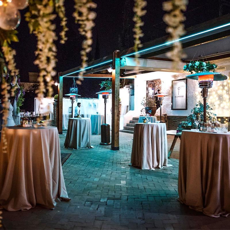 elcamborio-eventos-sociales-granada-21 Zona de cóctel en la terraza de El Camborio, iluminada de noche, preparada para un evento corporativo.