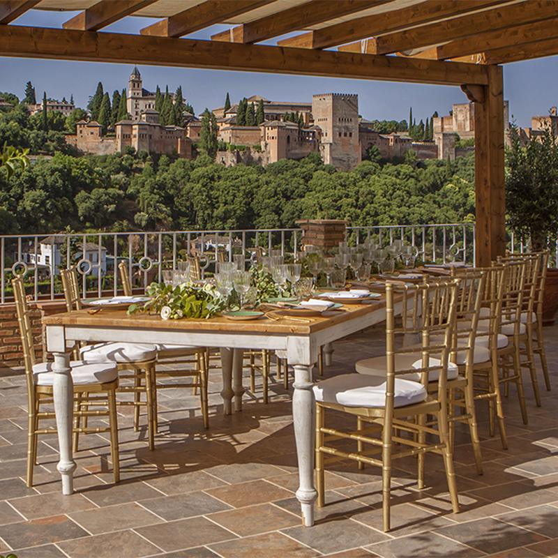 elcamborio-eventos-sociales-granada-29 Mesa larga de boda en El Camborio, elegantemente decorada en tonos blancos y verdes, con la Alhambra de Granada al fondo.