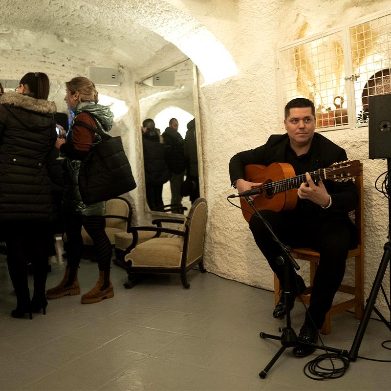 Invitados en un evento corporativo en la cueva de El Camborio, con una guitarrista tocando guitarra española como parte de la animación.