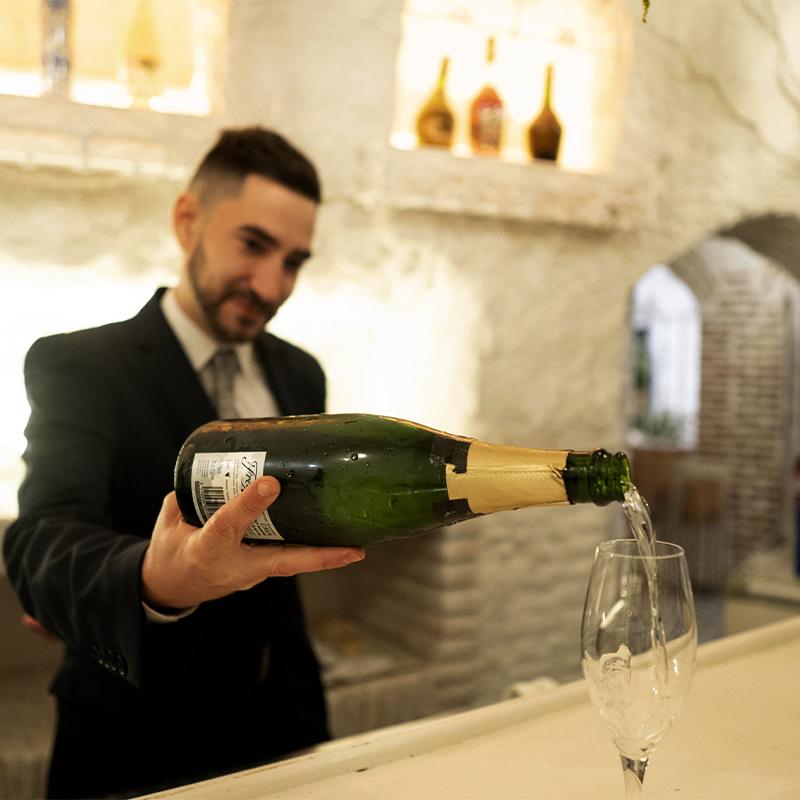Camarero sirviendo cava en la barra de la cueva de El Camborio durante un evento corporativo.