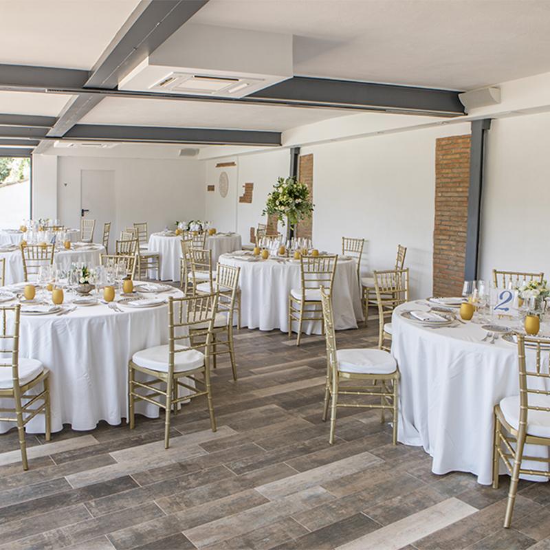 elcamborio-eventos-sociales-granada-4 Salón interior de El Camborio preparado para una boda, con varias mesas elegantemente decoradas con vajilla, flores y detalles festivos.
