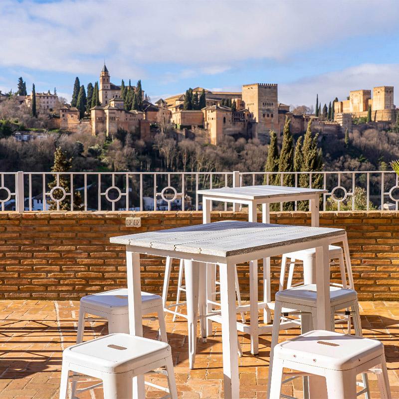 eventos-corporativos-elcamborio-granada-11 Montaje de zona de cóctel en El Camborio preparado para un evento social, con mesas altas, decoración elegante y ambiente acogedor.