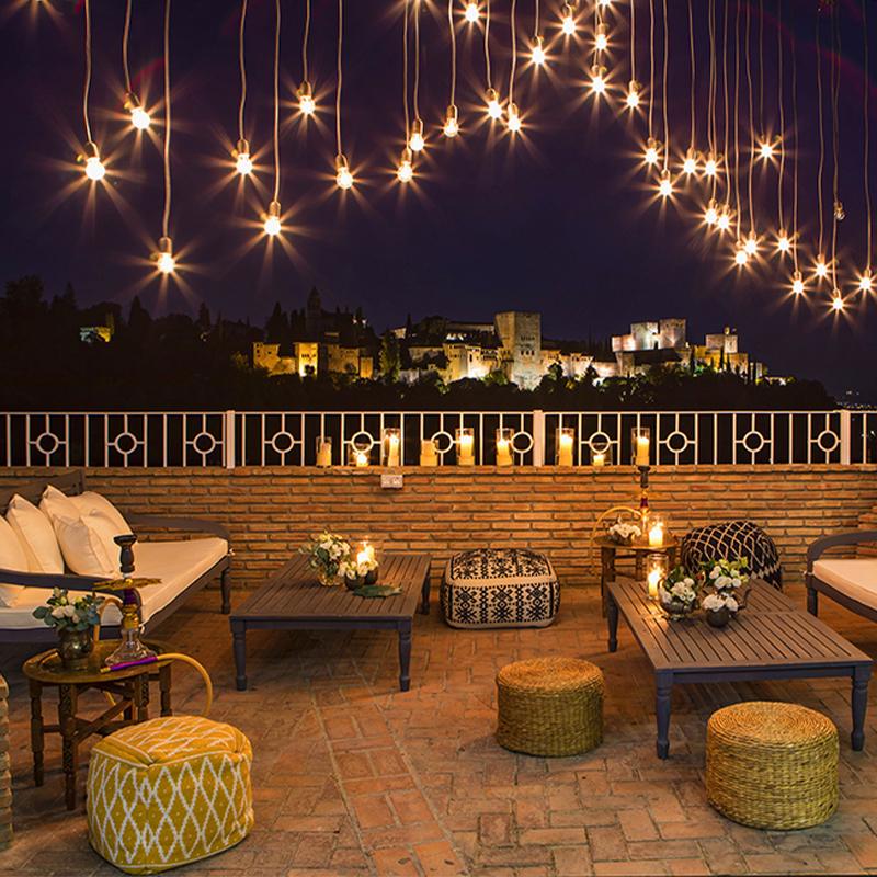 Zona chill out nocturna en El Camborio con iluminación cálida y vistas a la Alhambra de Granada